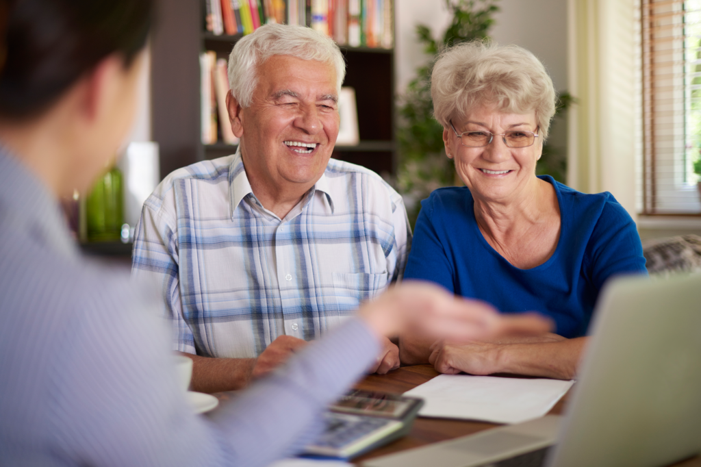 Back view of friendly insurance agent greeting senior clients with handshake while having meeting at cozy office